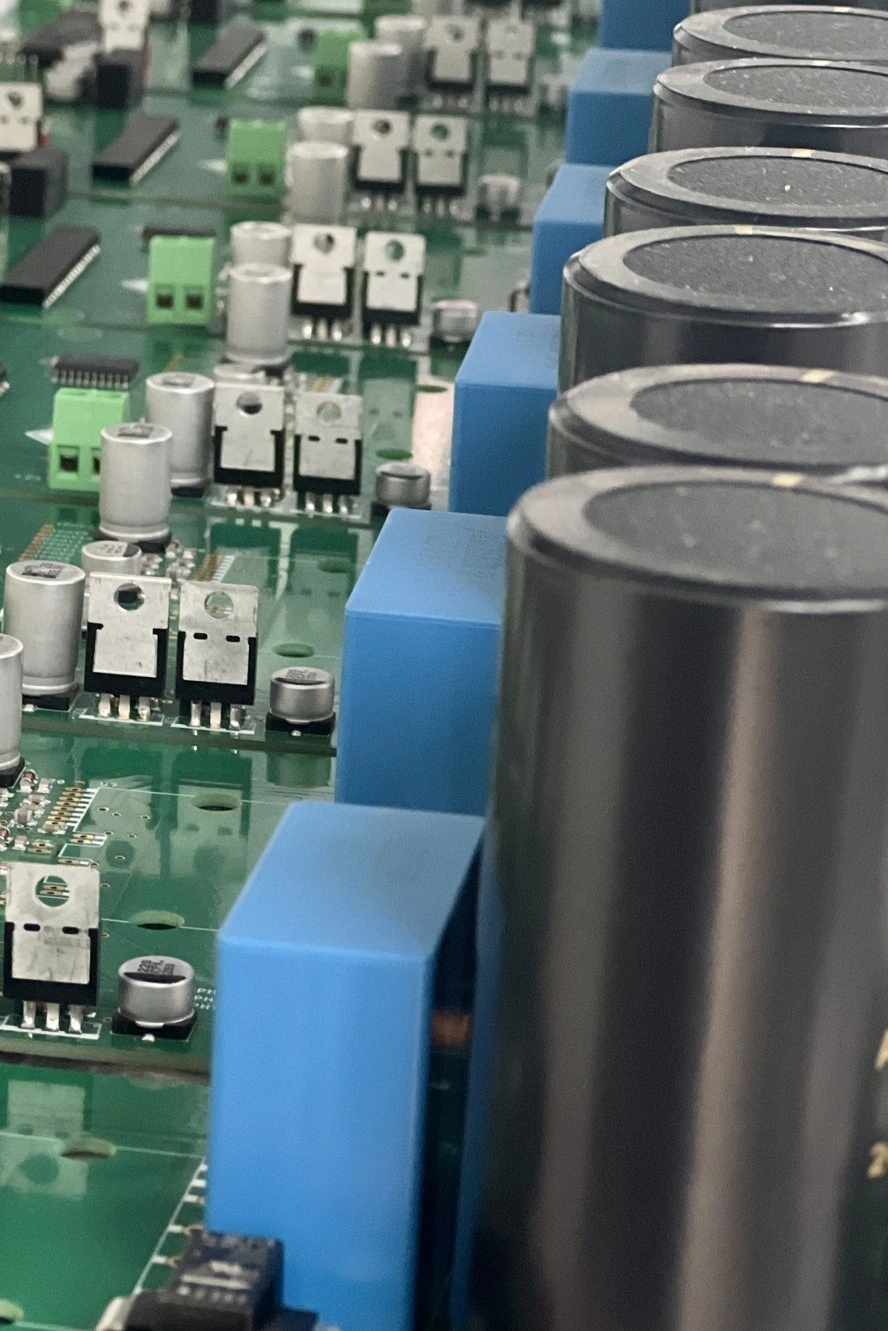 Mehrere bestueckte Leiterplatten in der Serienfertigung mit Leistungskomponenten und grossen Kondensatoren.